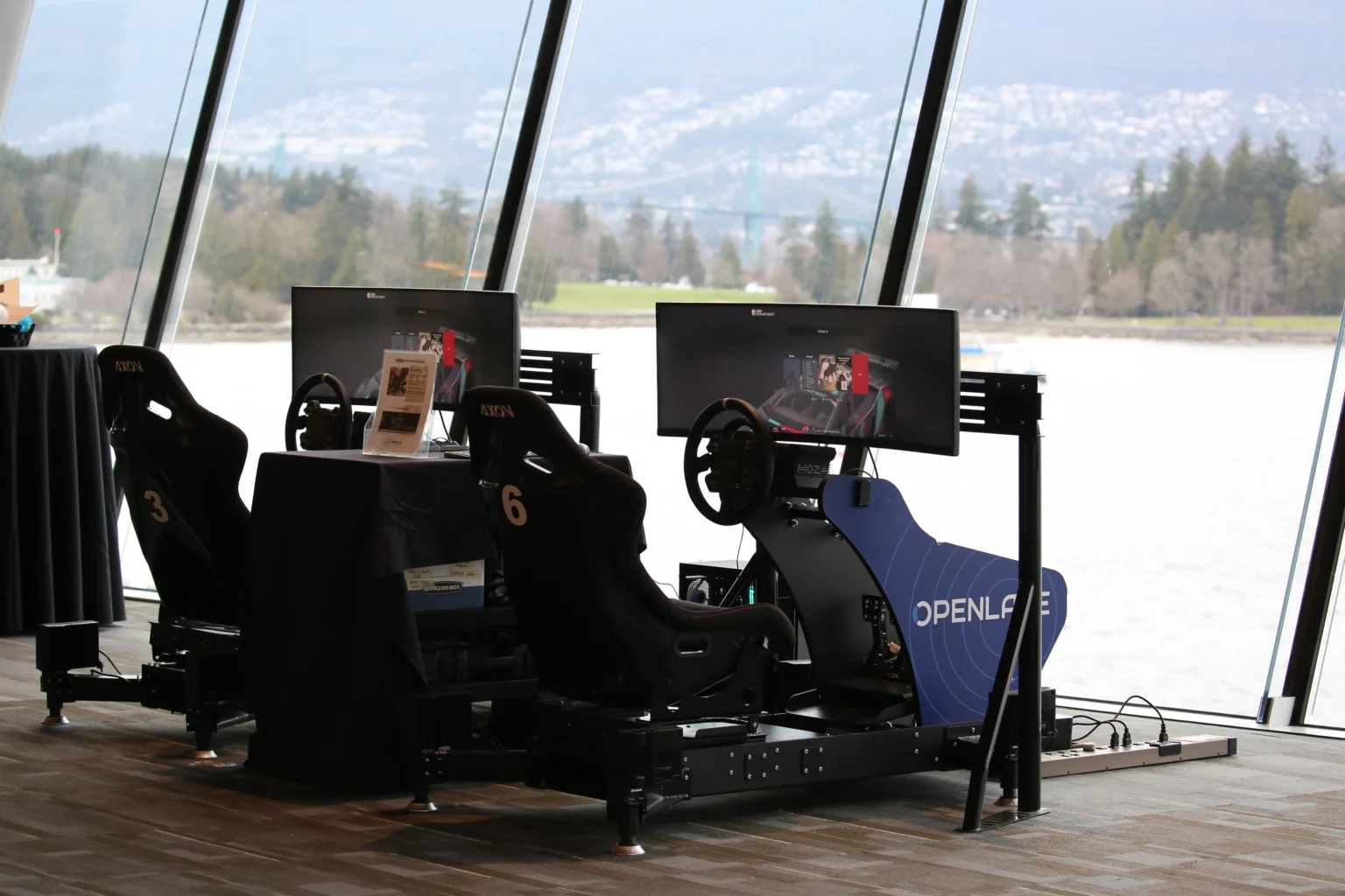 Two Axon simulators in Openlane branding, set up by the waterfront windows at the Vancouver Auto Show gala