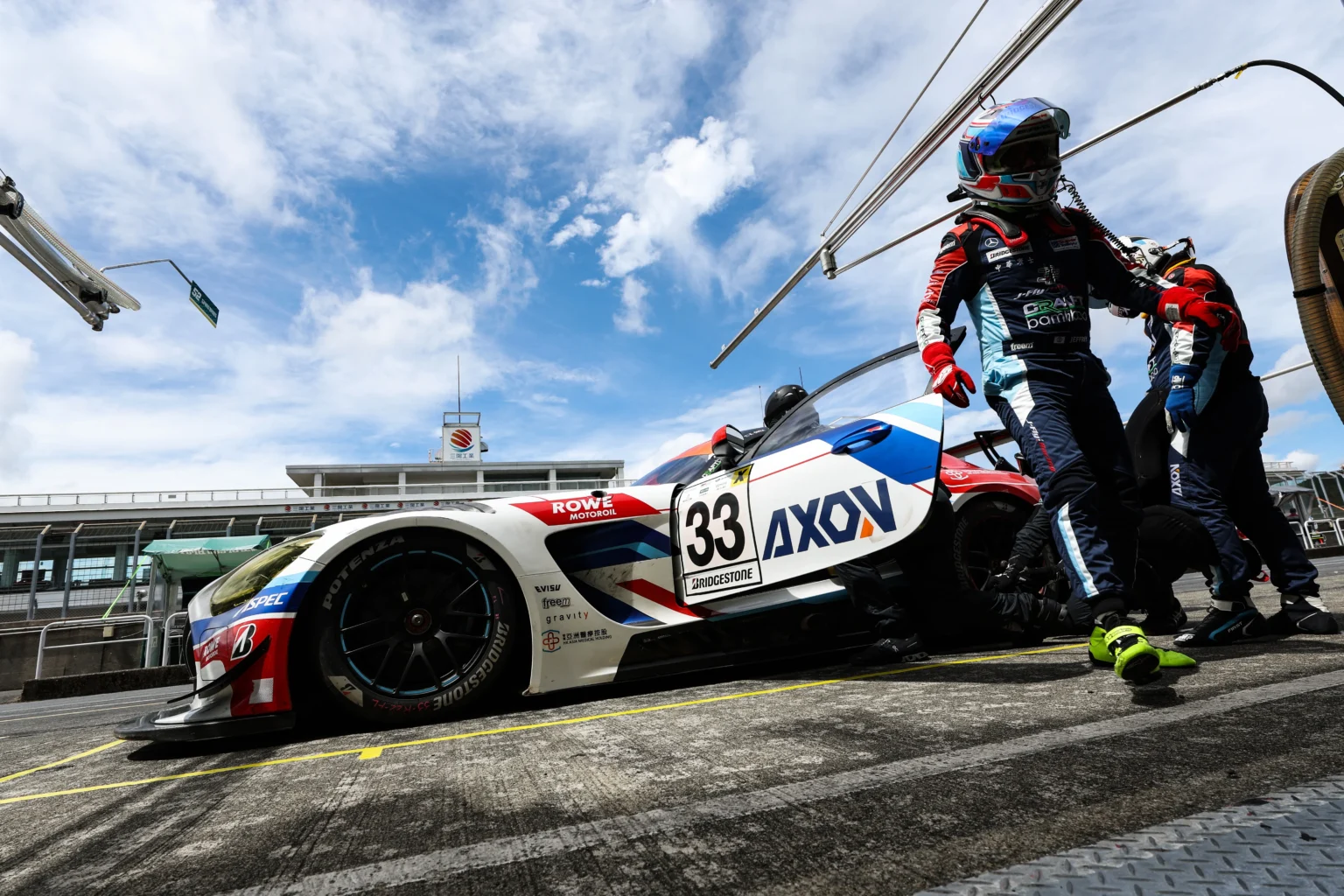 The AXON number 33 GT3 car during a pit stop, crew working over the car