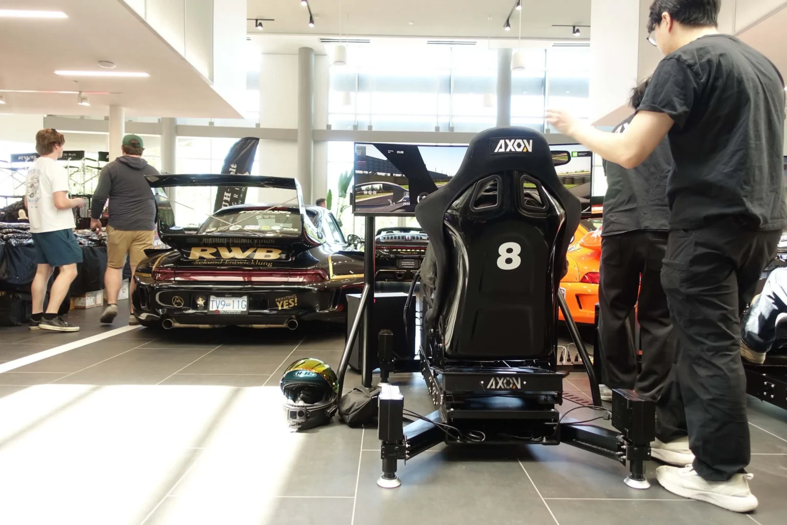An Axon simulator on the showroom floor at Porsche Centre Richmond, beside an RWB widebody Porsche