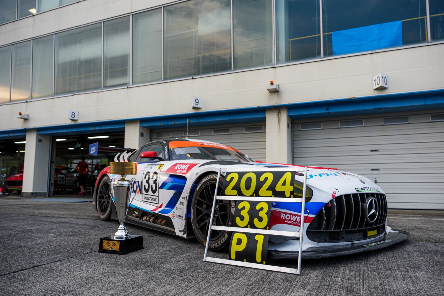 The AXON number 33 car with its winner's trophy and a P1 board after the Autopolis 5 Hours, 2024