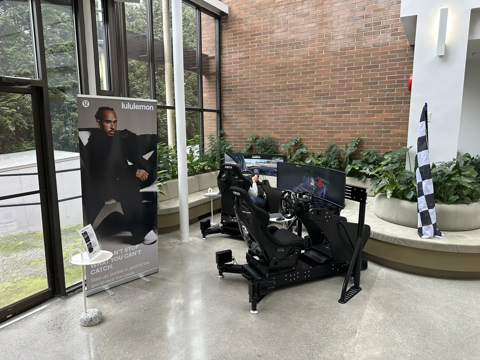 An Axon simulator set up alongside a Lewis Hamilton campaign banner at a Lululemon event